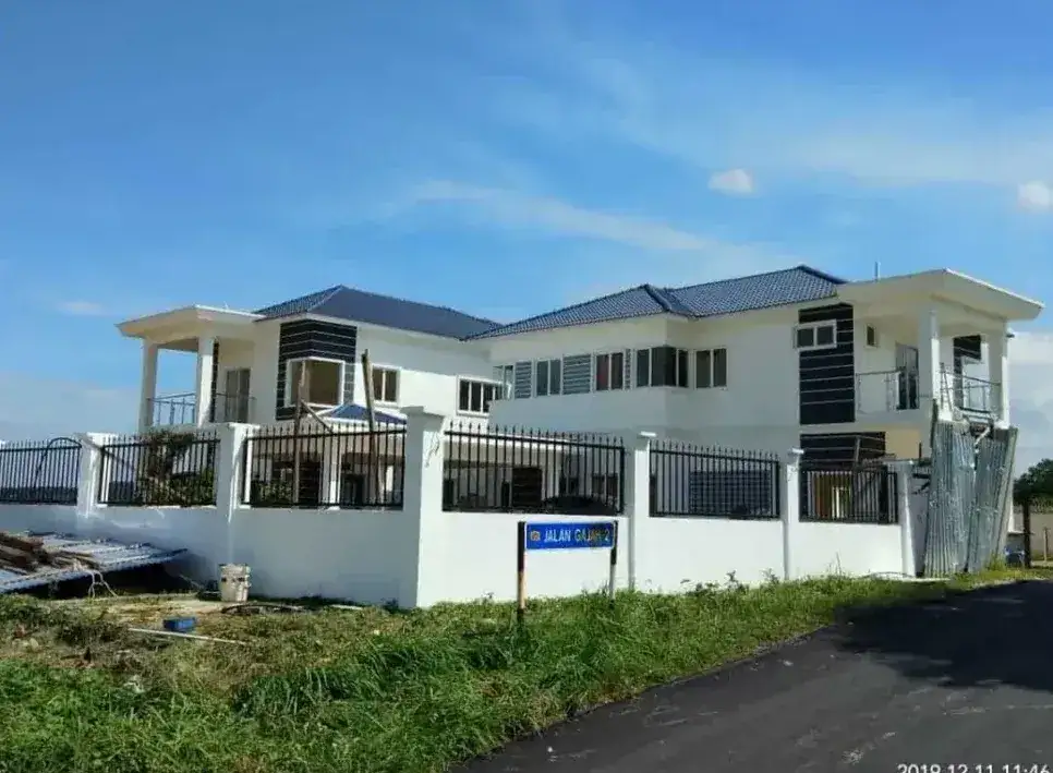A completed double-storey bungalow behind a white fence